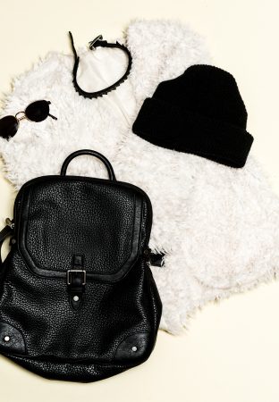 Black fashion set. Fur coat and black accessories. Bag, sunglasses. Bijouterie